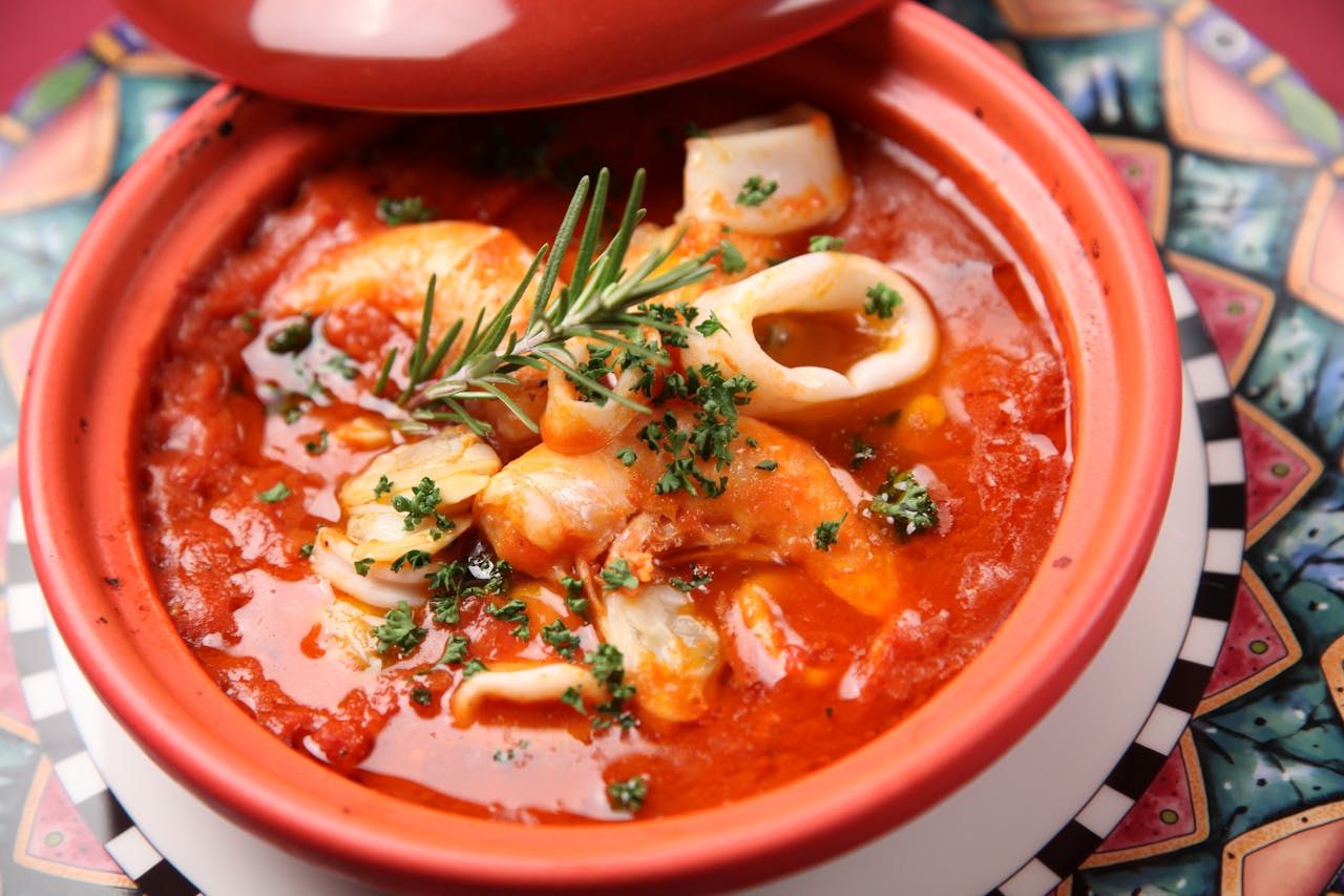 services-04 Savor this flavorful seafood stew with squid and shrimp in a rich tomato broth.