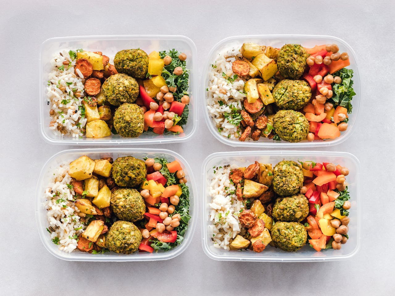 services-02 Colorful meal prep containers with falafel, chickpeas, rice, and vegetables for a healthy lifestyle.
